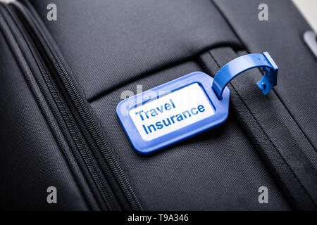 Close-up Of Travel Insurance Luggage Tag Tied To A Black Suitcase Stock Photo