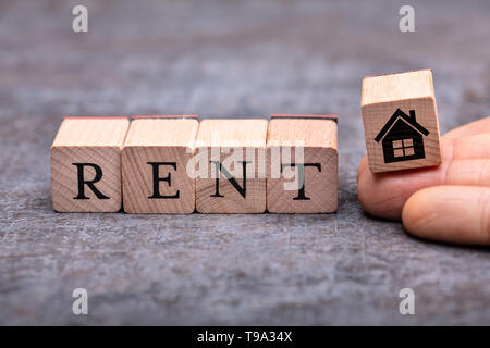 Close-up Of Person's Hand Placing House Icon Wooden Block Beside Rent Word Blocks Stock Photo