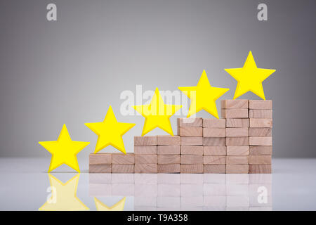 Yellow Stars On Wooden Blocks Over Reflective Desk Stock Photo