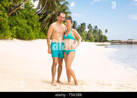 Portrait Of A Smiling Young Couple Looking To Camera At Beach Stock Photo