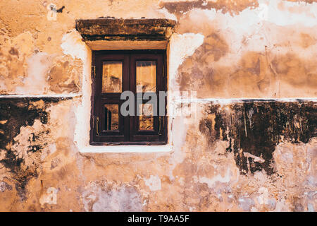 Vintage tone old white wooden window on the rustic yellow concrete wall facade background Stock Photo
