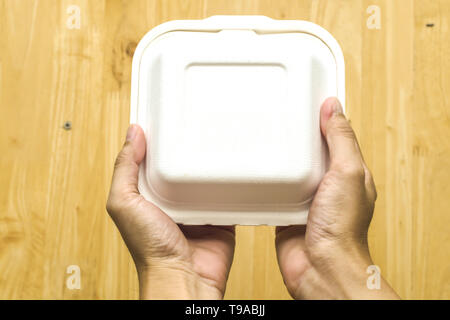 Close up hand  hold cake dessert in unmarked clear empty blank cardboard box, food order .Delivery concept.  Advertising area Receiving package mock u Stock Photo