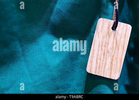 wooden tag with thin leather cord blue green canvas close up texture background Stock Photo