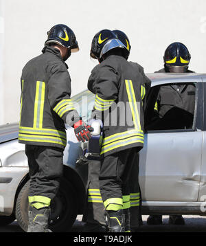 fire brigade team opens the door of the destroyed car with a large, powerful shear after the road accident Stock Photo