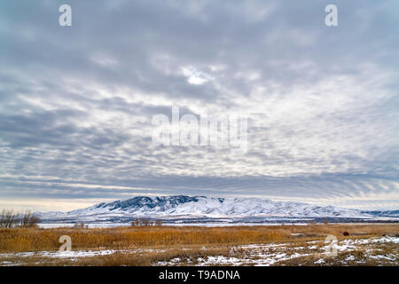Dramatic sky filled with cottony clouds over a scenic landscape in winter Stock Photo