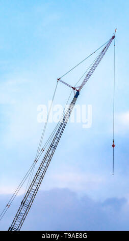Clear Vertical A lifting crane viewed against a beautiful blue sky filled with cottony clouds Stock Photo