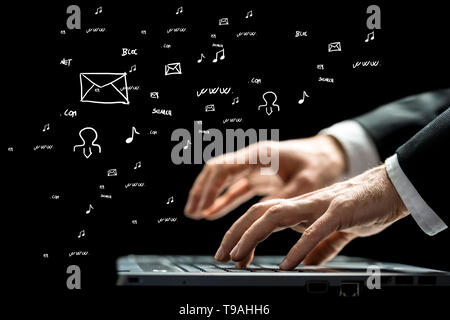 Businessman typing on a computer keyboard against a blackboard with hand-drawn business and computer icons scattered randomly, low angle view. Stock Photo