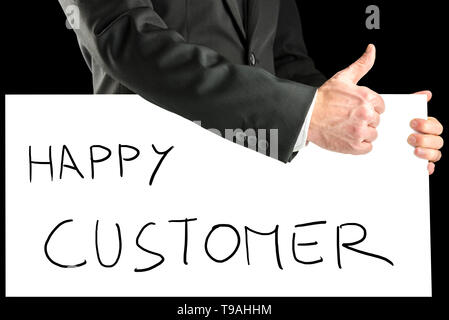 Businessman with a hand written sign saying - Happy customer - giving a thumbs up gesture to show his approval and support, closeup view of his arm. Stock Photo