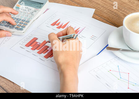 Closeup of female financial adviser or accountant looking at graphs and charts while using calculator. Stock Photo