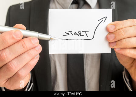 Closeup of businessman showing a white card with quickly ascending arrow and word start. Conceptual of vision and perspective of newly build business. Stock Photo