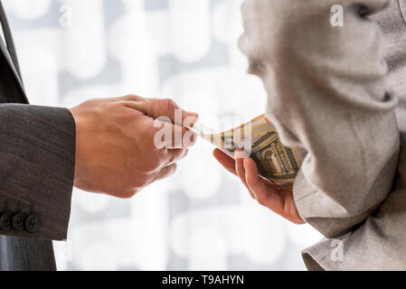 Businessman or politician taking bribe from a female colleague handing him Euro money from behind her back. Conceptual of corruption and bribery. Stock Photo