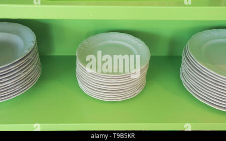 Set of white vintage plates on green shelf, antique tableware Stock Photo