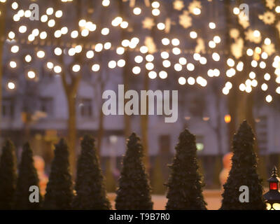 Christmas trees standing on the street under the luminous garlands Stock Photo
