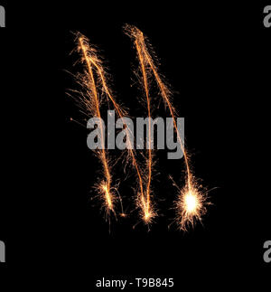 Sparklers forming letter M on dark background Stock Photo
