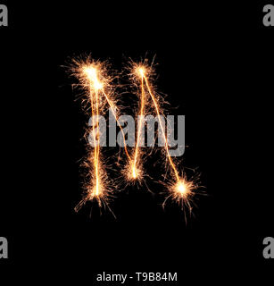 Sparklers forming letter M on dark background Stock Photo