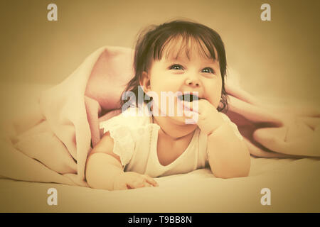 Portrait of happy baby girl lying on blanket at home Stock Photo