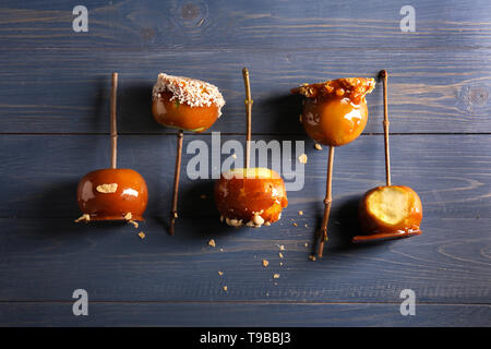 Delicious caramel apples with tree branches on color wooden table Stock Photo