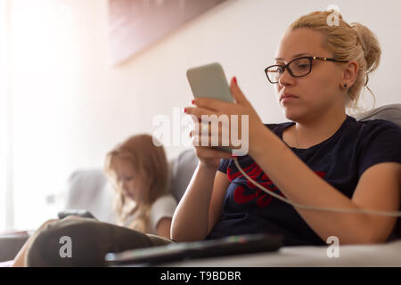 Woman and child looks busy with gadgets Stock Photo