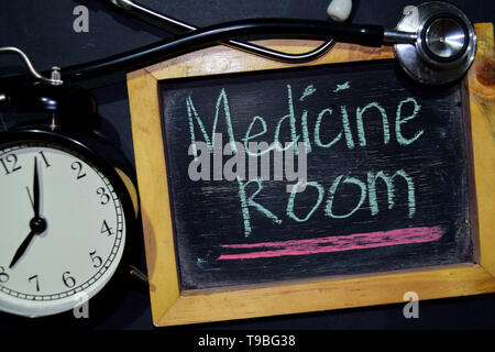 The words Medicine Room handwriting on chalkboard on top view. Alarm clock, stethoscope on black background. With education, medical and health concep Stock Photo