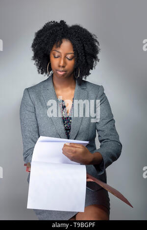 Black African American Businesswoman sitting and holding a folder of contracts or documents.  She looks like a secretary or a manager giving a busines Stock Photo