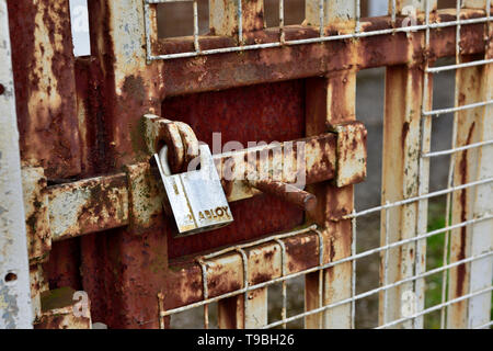 Padlock on rusty outdoor steel security gate with sliding bolt Stock Photo