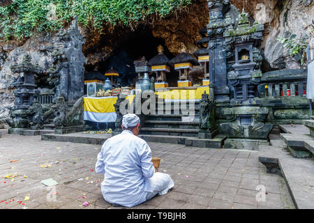 Hindu priest praying at Pura Goa Lawah ('Bat Cave Temple'), Balinese Hindu temple in Pesinggahan, Klungkung, Bali, Indonesia. Stock Photo