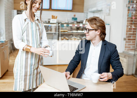 Young businessman with pretty waitress ordering some dessert at the cafe or pastry shop Stock Photo