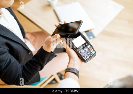Businessman paying contactless with smart phone while sitting at the cafe, close-up view Stock Photo