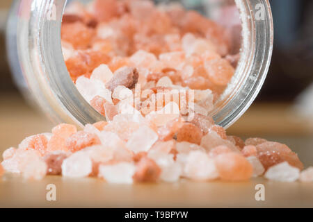 Himalayan pink rock salt in a bottle container on a wooden surface. Stock Photo