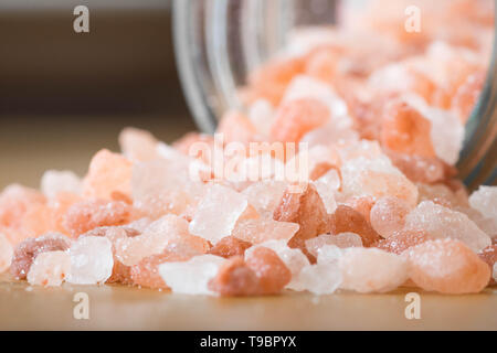 Himalayan pink rock salt in a bottle container on a wooden surface. Stock Photo
