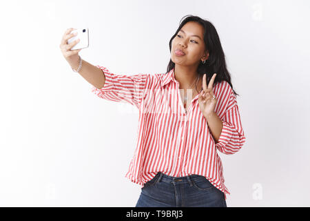 Good-looking feminine fashion blogger shaping heart with hands over chest,  folding lips in kiss, giving mwah, taking photo for fan base, standing over  gray wall with cute bun hairstyle in glasses Stock Photo - Alamy