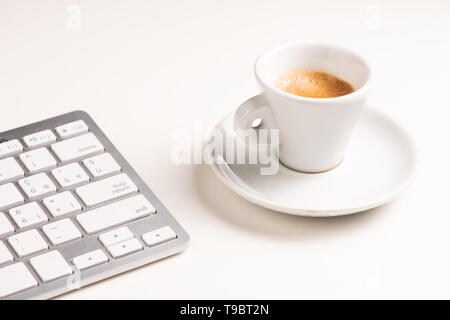 A close up view of arranged computer keyboard,cup of coffee on white table. Close up Stock Photo