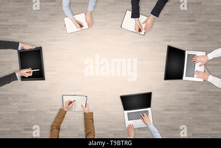 Group of people with devices in hands having desk discussion and making reports together on laptop, tablet, notebook  Stock Photo