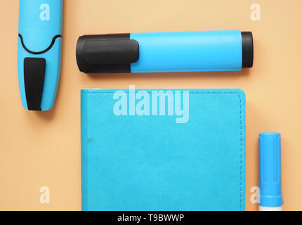 Top view of notepad and blue markers on an orange desk. Stock Photo