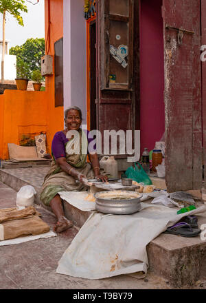 Vertical view of a lady making paratha on her doorstep in Fort Kochi, India. Stock Photo