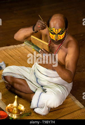 Vertical aerial view of a Kathakali performer applying his distinctive make up in Kerala, India. Stock Photo