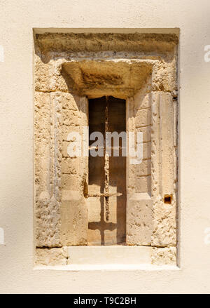 An ancient stone window with a rusty window grid inside the inner courtyard of the Stadtschloss Dresden in Germany on a very sunny day. Stock Photo