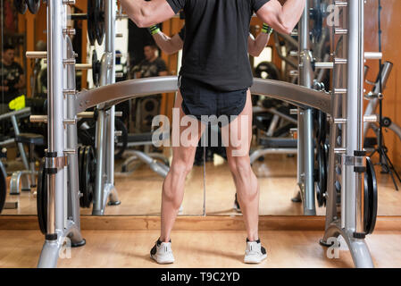 sport, bodybuilding, lifestyle and people concept - young man with barbell doing squats in gym . Stock Photo