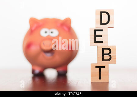 Piggy bank and debt word on wooden blocks Stock Photo