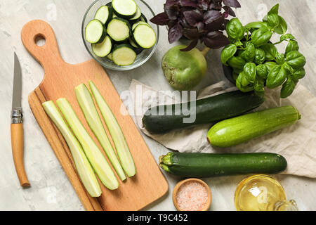 Fresh squashes with cutting board and basil on grey table Stock Photo