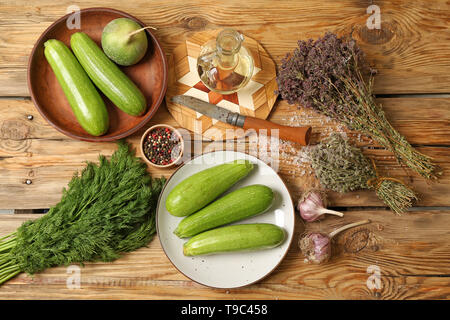 Plates with fresh squashes, spices and herbs on wooden table Stock Photo