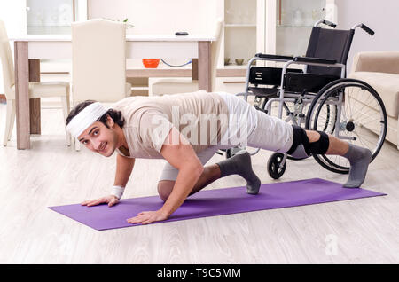 Injured young man doing exercises at home Stock Photo