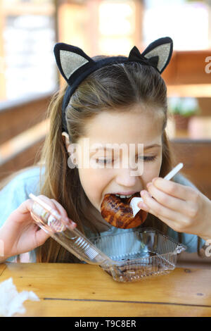 The girl in the cafe eats chocolate donuts Stock Photo
