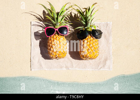 An Overhead View Of Two Pineapple Lying On Towel On The Beach Stock Photo