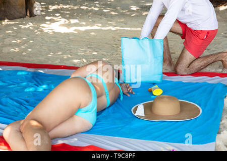 Close-up Of Thief Stealing From A Woman's Bag Sleeping On The Blanket On The Beach Stock Photo
