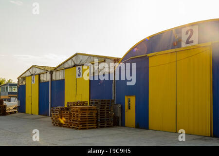 three storage houses blue and yellow  with pallet on the front Stock Photo