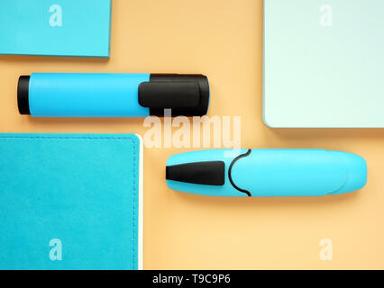 Blue notepads and markers on an orange surface. Top view flat lay of office supply. Stock Photo