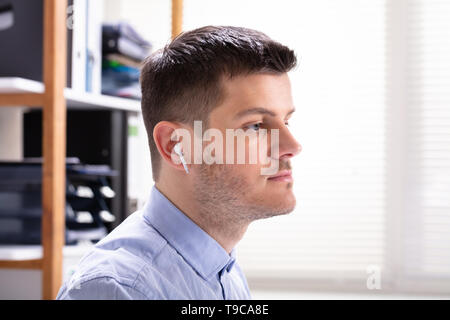 Close-up Of Man Listening To Music Uses Modern Wireless Earphone Stock Photo