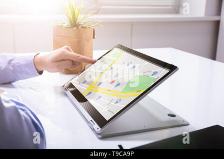 Close-up Of A Person's Hand Using GPS Service On Digital Laptop Stock Photo