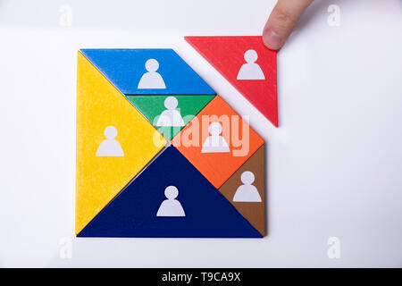 Businessman's Hand Building Tangram Square Block With Human Figures Stock Photo